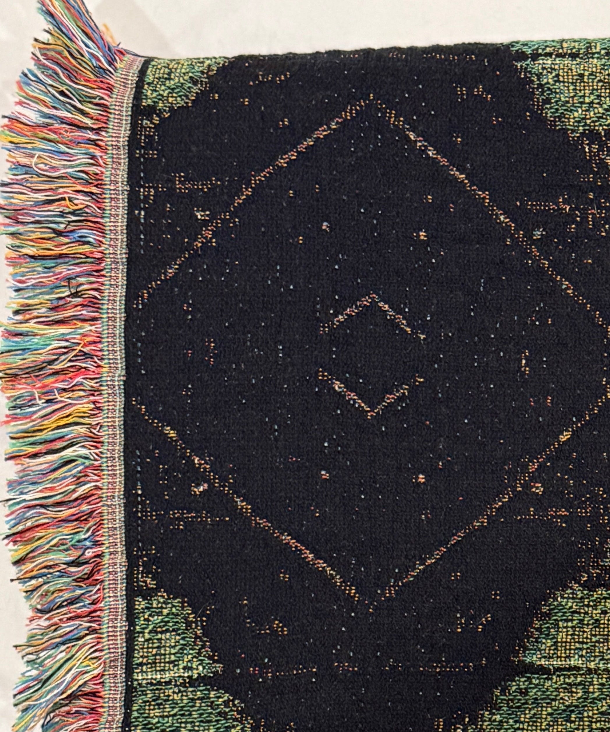 Woven blanket with geometric pattern and fringes on a white background