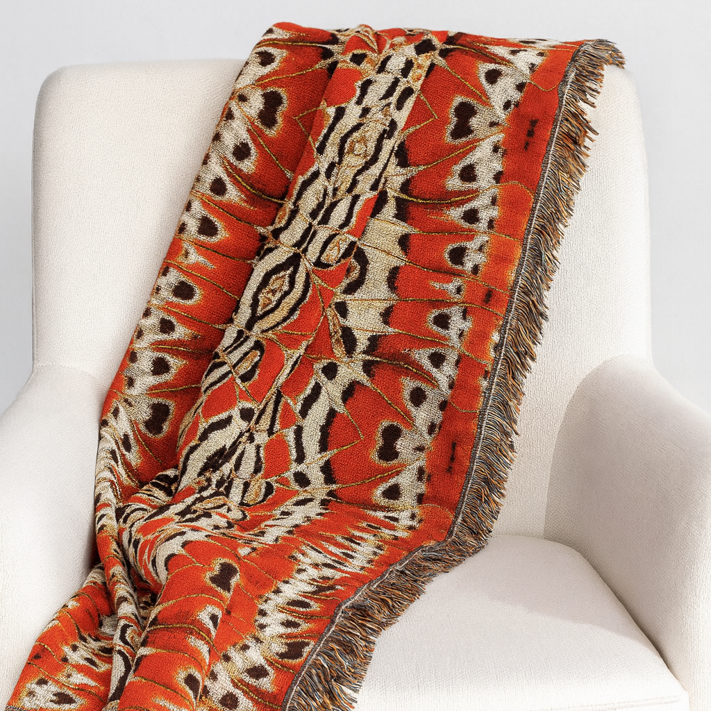 Decorative blanket with orange and brown pattern draped over a white chair.