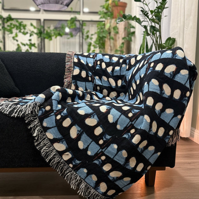 Black sofa with a blue and white patterned throw blanket in a living room setting.